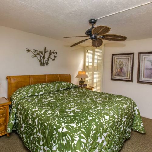 King size bed, ceiling fan, storage, and sitting chair in bedroom