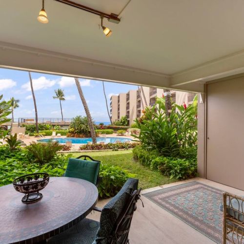 Large shaded lanai with dining table for 4 people and 2 sitting chairs.