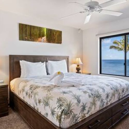 Main bedroom features a king size bed, ceiling fan, dresser, and ocean view