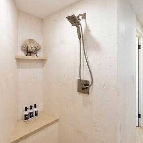 Beautiful custom travertine walk in shower with luxury organic bath products courtesy of Stay Aloha