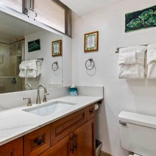 Quartz countertop single sink vanity, fresh linens, and lux organic bath products