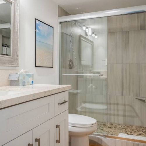 Remodeled bathroom includes walk in shower, new toilet, & new modern single sink vanity.